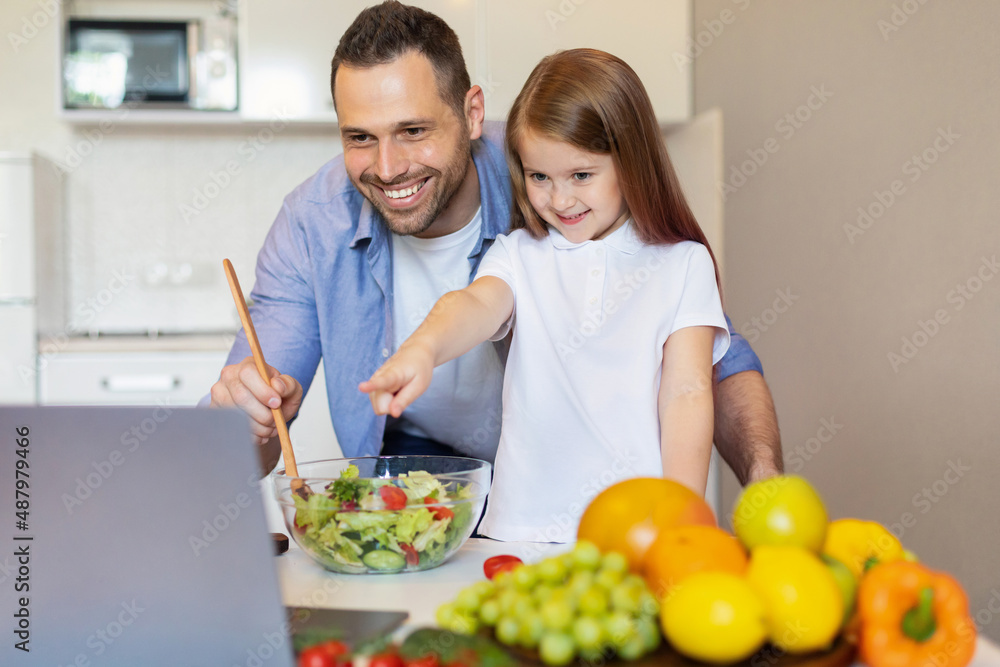 Dad And Daughter Cooking Using Laptop Making Salad At Home Dad And Daughter Cooking Using Laptop Making Salad At Home