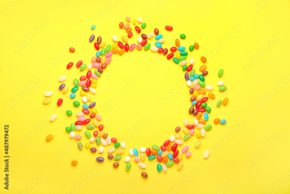 Frame made of different jelly beans on yellow background