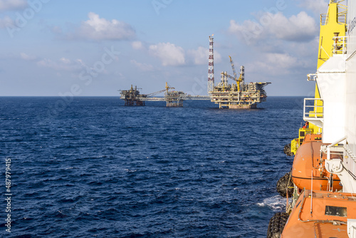 A landscape of an oil production platform viewed from a pipelaying construction work barge at offshore oil field