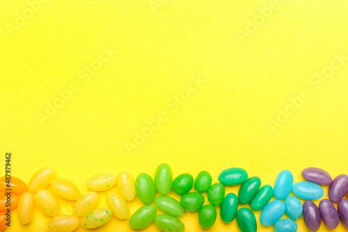 Different jelly beans on yellow background photo