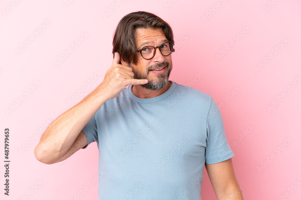 Senior dutch man isolated on pink background With glasses and doing phone gesture Senior dutch man isolated on pink background With glasses and doing phone gesture