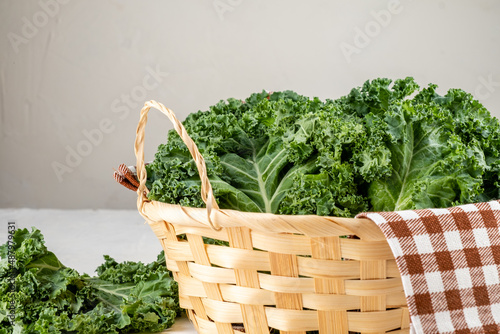 Fresh kale leaves in a wooden basket on a gray background. photo