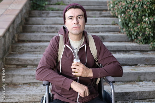 Depressed man on a wheelchair holding beer bottle