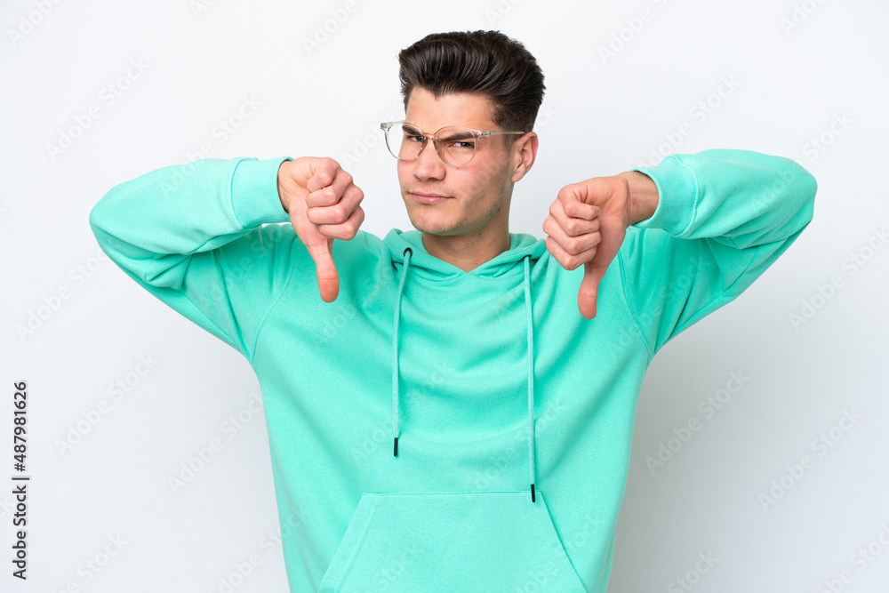 Young handsome caucasian man isolated on white bakcground showing thumb down with two hands Young handsome caucasian man isolated on white bakcground showing thumb down with two hands