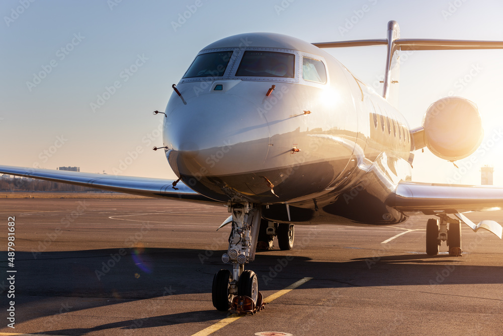 Scenic front view modern luxury expensive private jet plane parked airport taxiway hangar warm colorful dramatic evening warm sunset sun light sky background. Executive aicraft vip travel concept Scenic front view modern luxury expensive private jet plane parked airport taxiway hangar warm colorful dramatic evening warm sunset sun light sky background. Executive aicraft vip travel concept