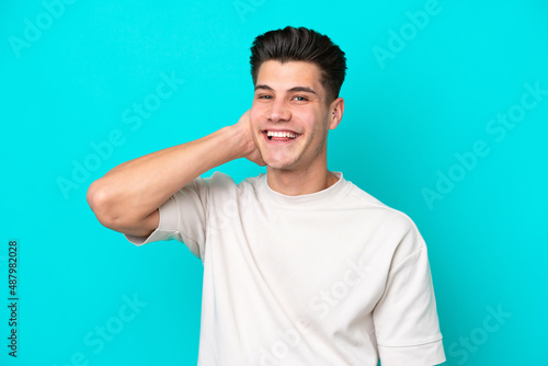Young handsome caucasian man isolated on blue bakcground laughing