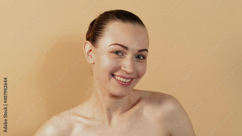 Portrait of an attractive nude caucasian girl touching her face and shoulders isolated on a beige studio background. Portrait of an attractive nude caucasian girl touching her face and shoulders isolated on a beige studio background.
