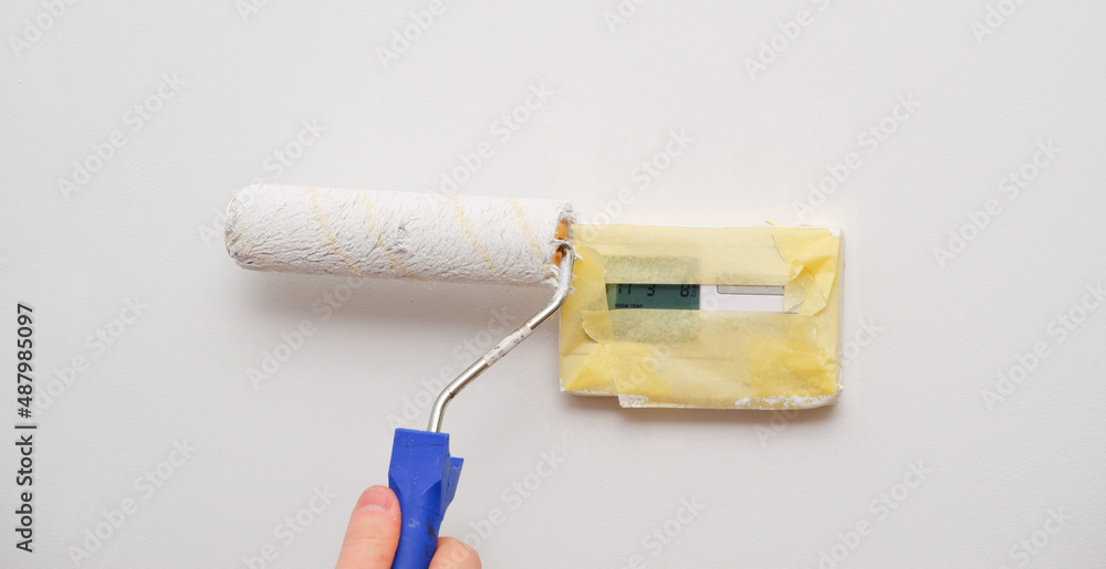 Painting works. A man paints a light wall with a paint roller. Close-up on a hand with a tool. Construction worker, tool, apartment renovation. Painting works. A man paints a light wall with a paint roller. Close-up on a hand with a tool. Construction worker, tool, apartment renovation.