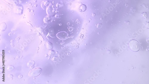 Bakuchiol serum transparent texture with slowly moving bubbles, purple liquid skincare cosmetic gel, macro shot.