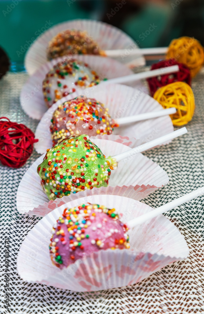 candy on a stick in a multicolored sprinkle on the counter candy on a stick in a multicolored sprinkle on the counter