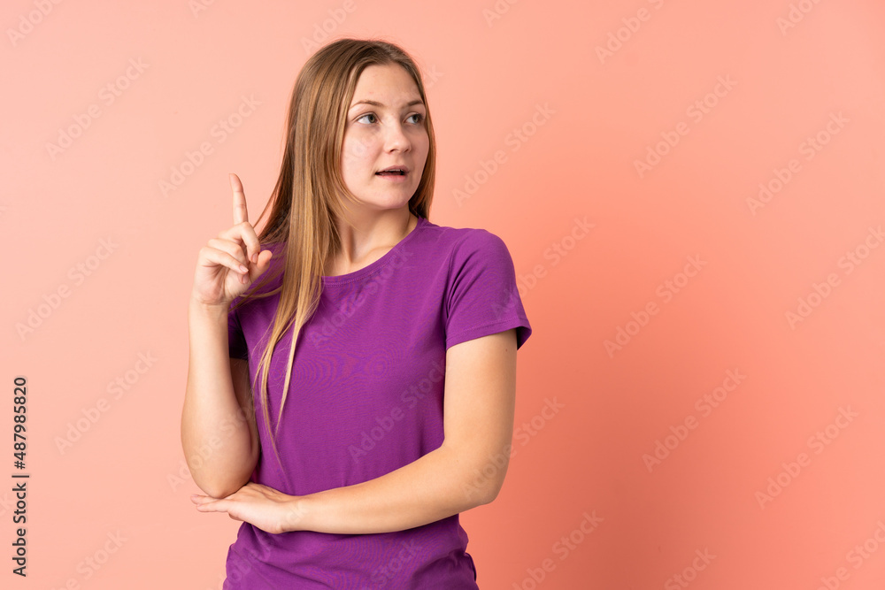 Obraz premium Teenager Ukrainian girl isolated on pink background thinking an idea pointing the finger up