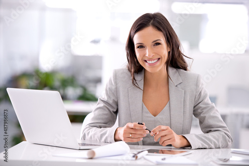 Shes made it. Shot of an attractive businesswoman sitting at her desk in an office. photo