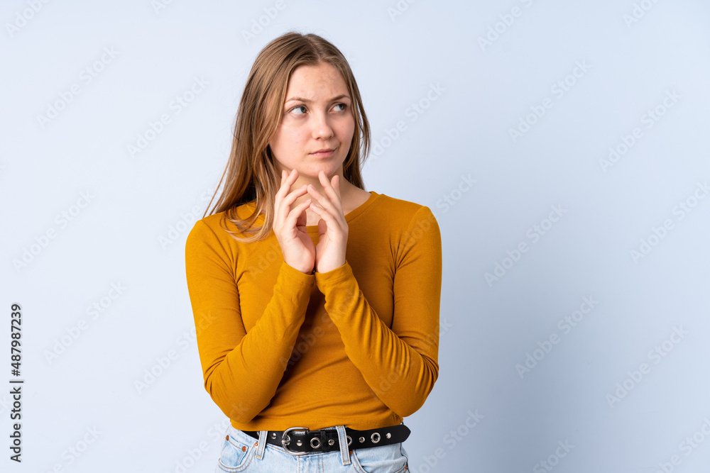 Teenager Ukrainian girl isolated on blue background scheming something Teenager Ukrainian girl isolated on blue background scheming something