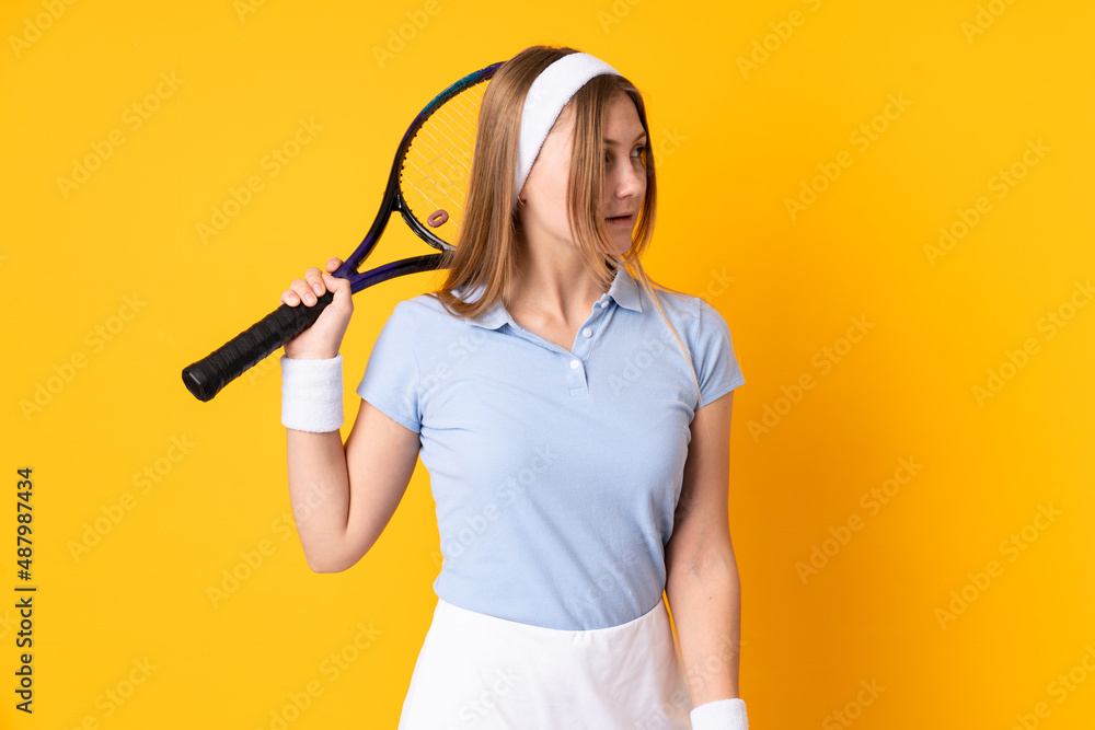 Teenager Ukrainian girl tennis player isolated on yellow background playing tennis Teenager Ukrainian girl tennis player isolated on yellow background playing tennis