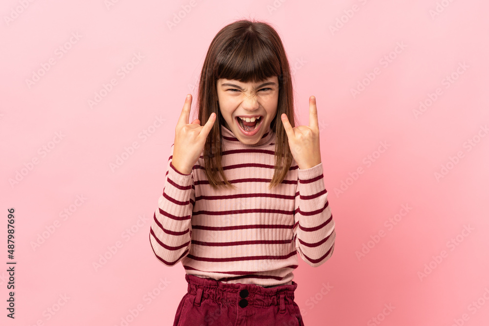 Little girl isolated on pink background making horn gesture Little girl isolated on pink background making horn gesture