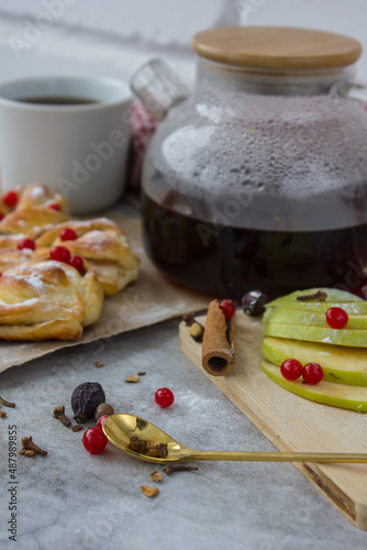 cozy and delicious breacfast with black tea in a transparent kettle, a piece of pie, apple slices and spices photo