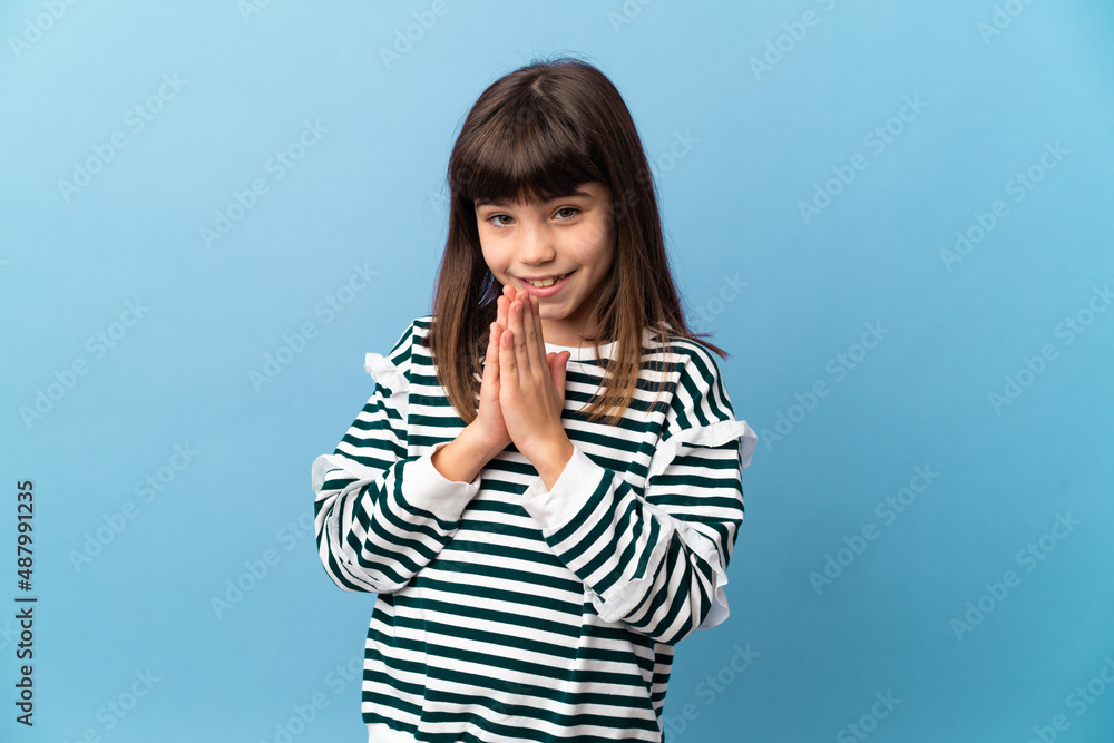 Little girl over isolated background keeps palm together. Person asks for something Little girl over isolated background keeps palm together. Person asks for something
