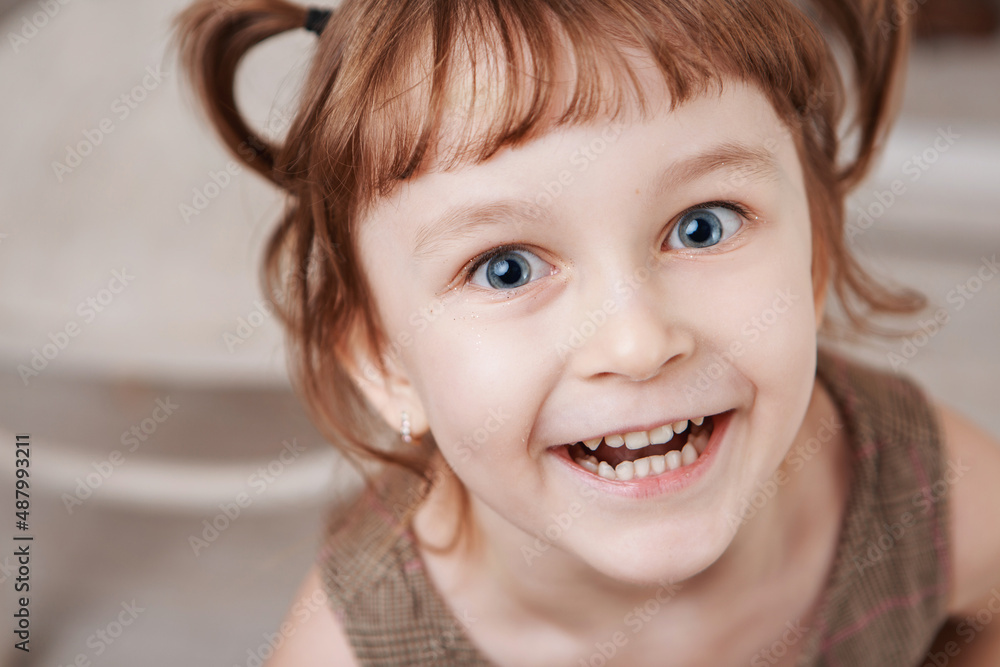 Cheerful positive adorable small child with two pony tails, dressed in striped t shirt, expresses pleasant emotions, being glad to recieve new toy from parents, copy space Cheerful positive adorable small child with two pony tails, dressed in striped t shirt, expresses pleasant emotions, being glad to recieve new toy from parents, copy space