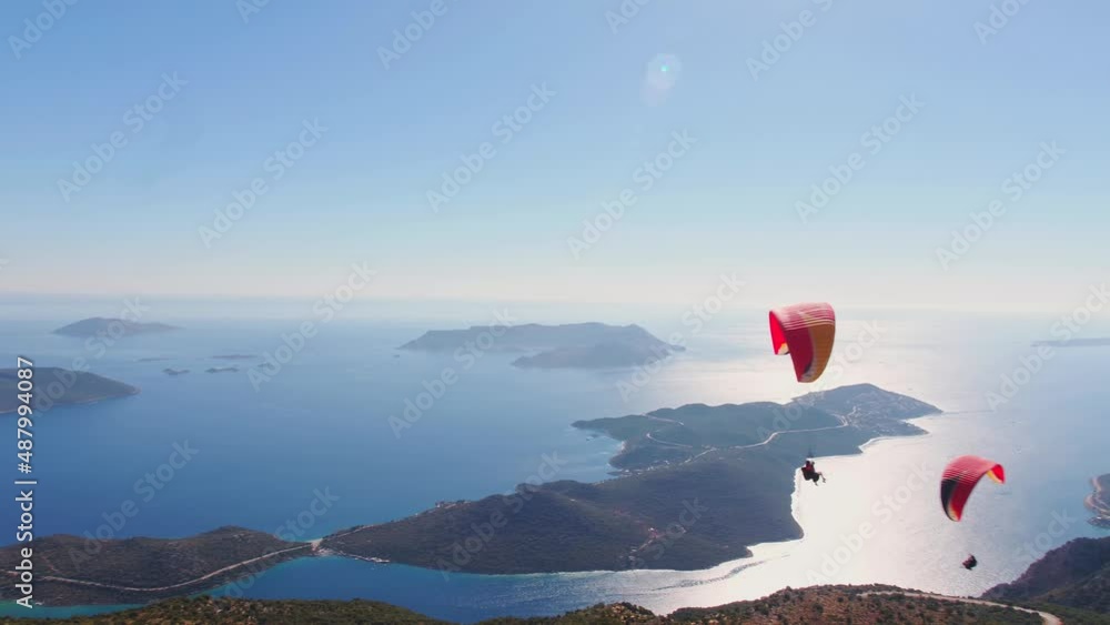 Aerial wide angle shoot of 2 tandem paragliders soaring in harmony - Panoramic Kas Antalya view in the background