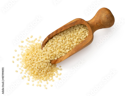 Hulled hemp seeds in the wooden spoon, isolated on white, top view.