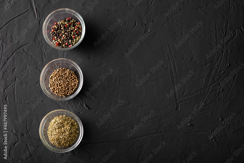 Various spices in three containers. Pepper, coriander, oregano. Dark background. Place for text.