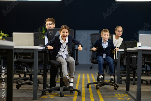 Business children having fun riding office chair