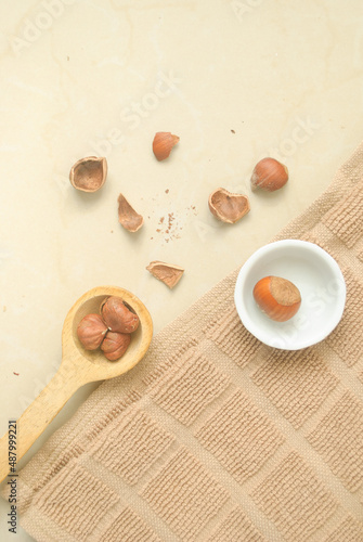 A wood spoon with nuts  a white plate with nuts  brown towel and a kitchen 