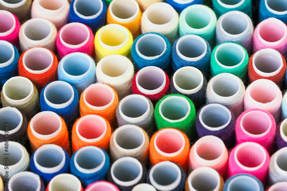 Sewing threads as a multicolored background. Yarn on a spool, yarn on a tube, cotton thread Sewing threads as a multicolored background. Yarn on a spool, yarn on a tube, cotton thread