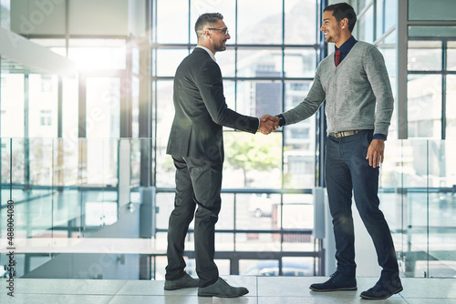 Working together for success. Shot of two businessmen shaking hands together in an office.