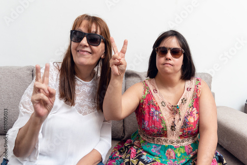 portrait of two latin adult women making V sign