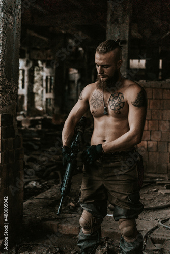 a soldier in military clothes poses in an abandoned building with a gun in his hands