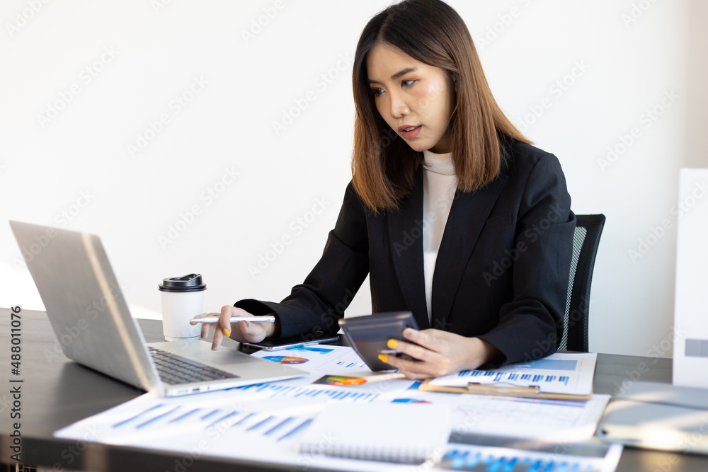 Businesswoman or accountant working in an office is analyzing accounting using laptop and calculator. Businesswoman or accountant working in an office is analyzing accounting using laptop and calculator.