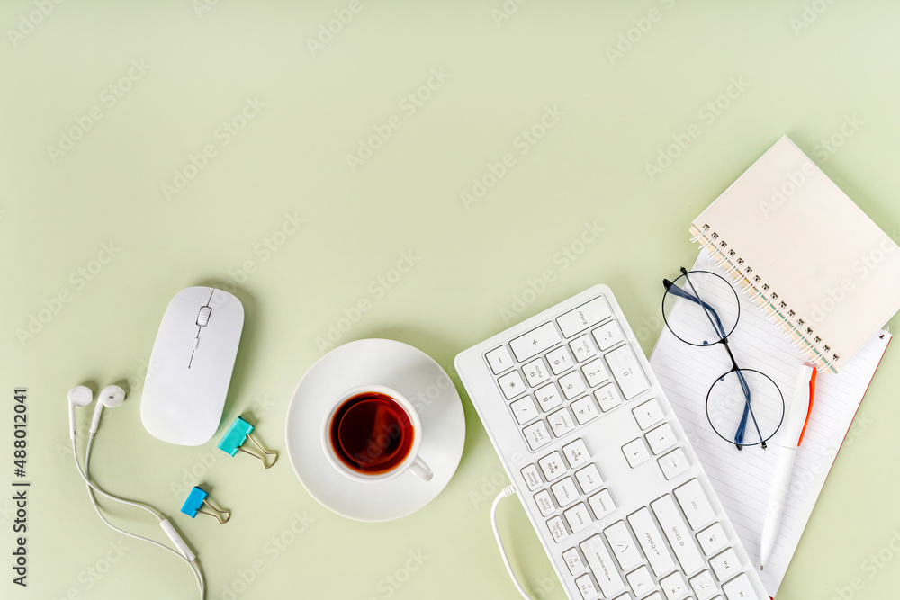 Light green office desk, minimalist style desk with keyboard, tea mug
