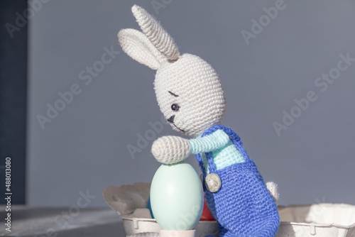 The Easter Bunny is on a wooden surface with painted eggs. photo