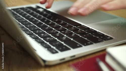 Close-up of woman hands typing on a laptop keyboard. Slow motion footage