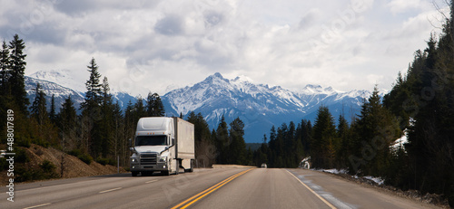 transport truck travelling on the Trans Canada Highway eastbound near Rogers Pass British Columbia in winter in good road conditions snow on Rocky Mountains in background horizontal format 