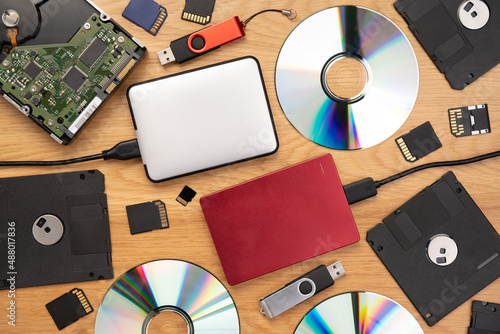 Data storage devices such as CDs, hard drives, pen drives and other, top view on a wooden background photo