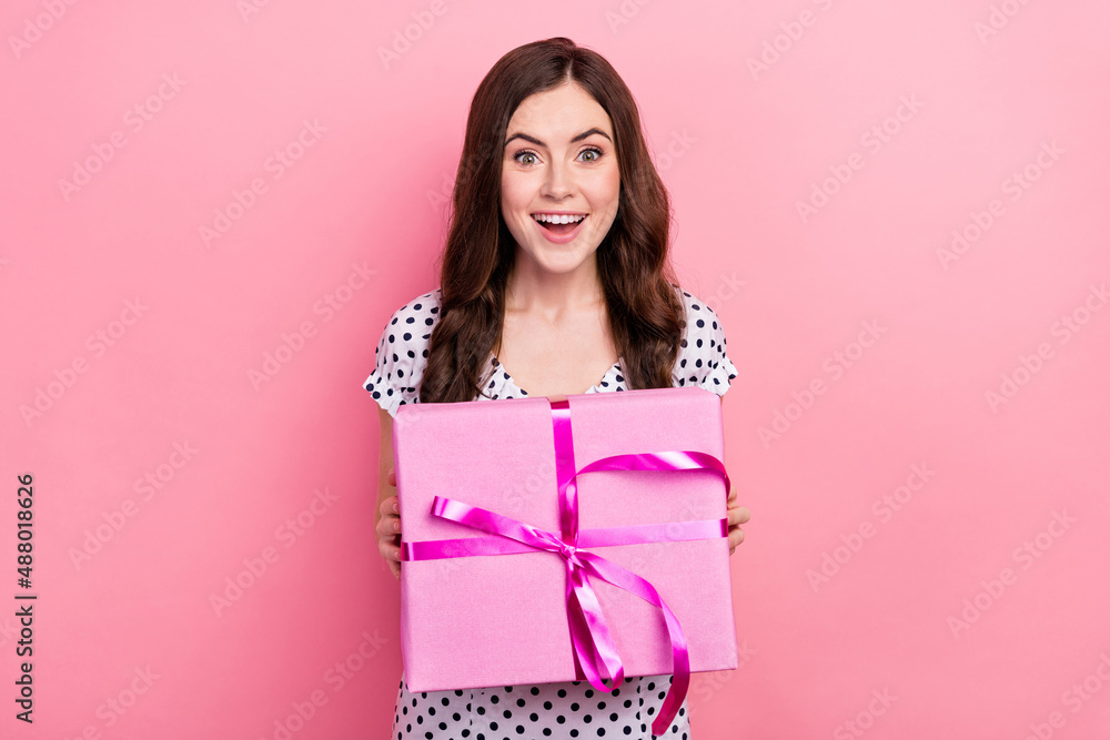 Photo of funky excited lady dressed dotted dress holding big present box smiling isolated pink color background Photo of funky excited lady dressed dotted dress holding big present box smiling isolated pink color background