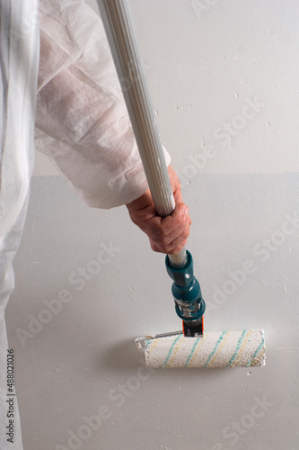 pintor pintando con rodillo pared en blanco, raya oscura de parquing