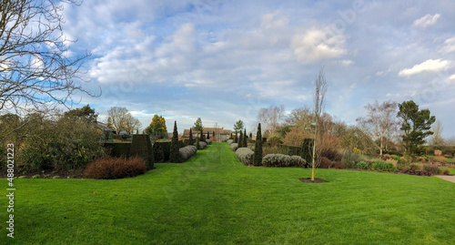 English winter garden with green grass and cloudy sky, the subject is out of focus, panorama, Hyde Hall, RHS, England