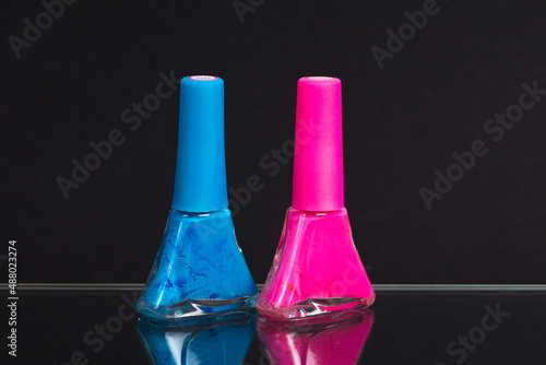 blue and pink nail polish on a black background
