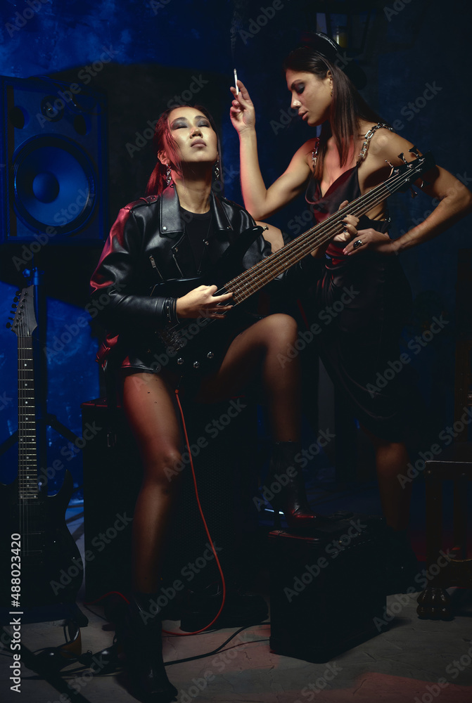 Women wear fashion clothes posing with cigarette and guitar Women wear fashion clothes posing with cigarette and guitar