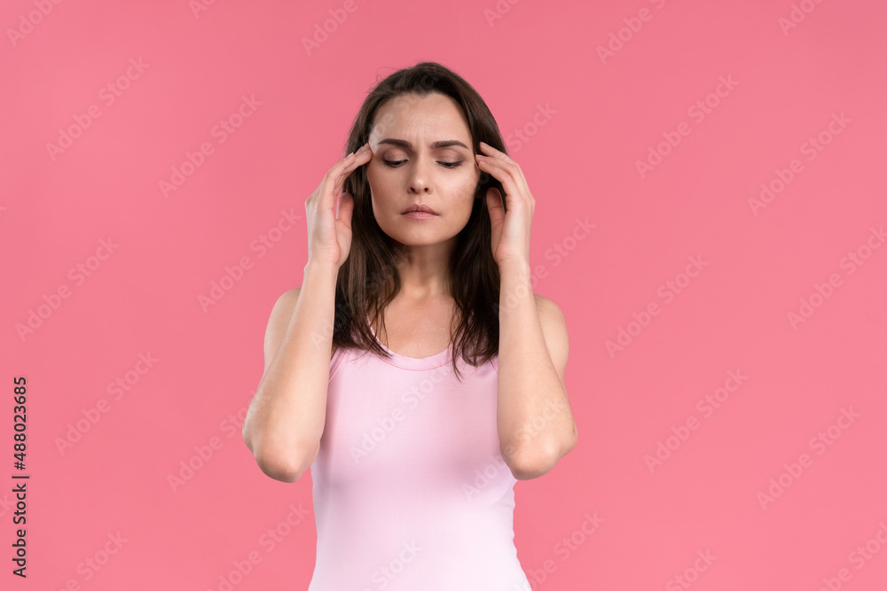 Stressed or having a headache businesswoman in suit holding her head with eyes shut isolated on pink background. Stressed employee woman in stripe suit Stressed or having a headache businesswoman in suit holding her head with eyes shut isolated on pink background. Stressed employee woman in stripe suit