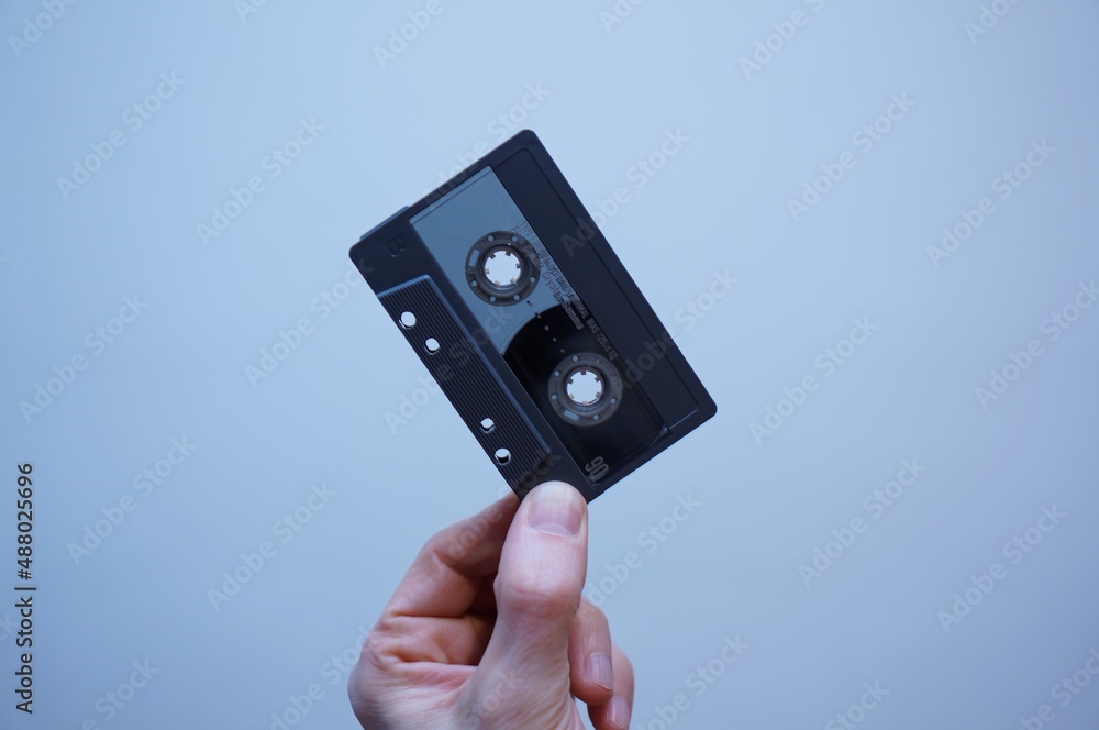 Audio tape in caucasian hand. 90-minute grey audio cassette. Analog tape. Vintage tech. Audio tape in caucasian hand. 90-minute grey audio cassette. Analog tape. Vintage tech.