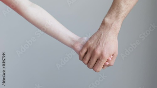 Man and child join hands and hold against the background of a white wall