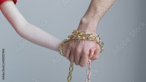 A child and a man hands are tied with a golden chain, holding and not letting go