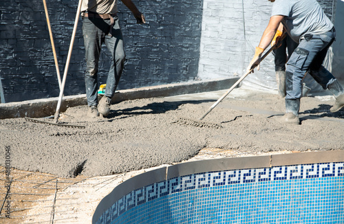 Workers distributing the concrete with rakes around the pool, fixing the garden © Elizabeth
