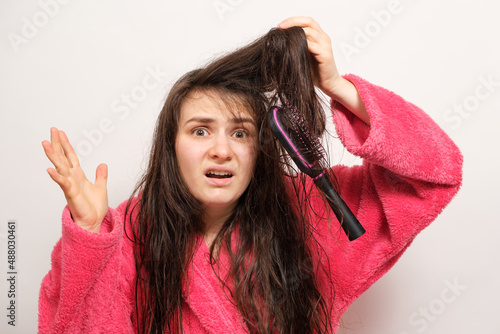 A woman with wet long tangled hair tries to comb photo