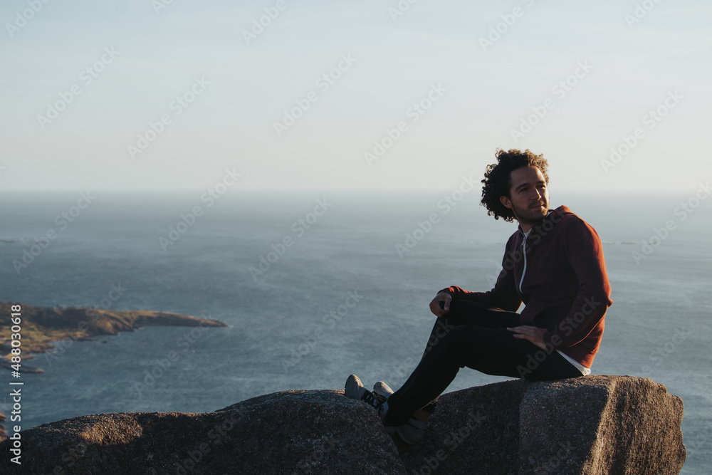 Man sitting on a rock looking at the sea