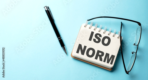 ISO NORM text written on a notepad on the blue background
